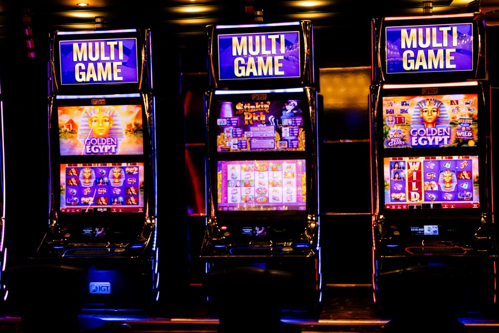 Tiga mesin slot bercahaya di kasino malam hari